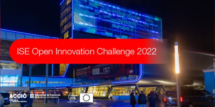 Edifici integrated systems europe de nit amb frase ISE Open Innovation Challenge 2022 en lletres blanques sobre requadre vermell